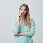 Blonde woman in turquoise shirt wonders what to do about her shifted bite and crooked teeth