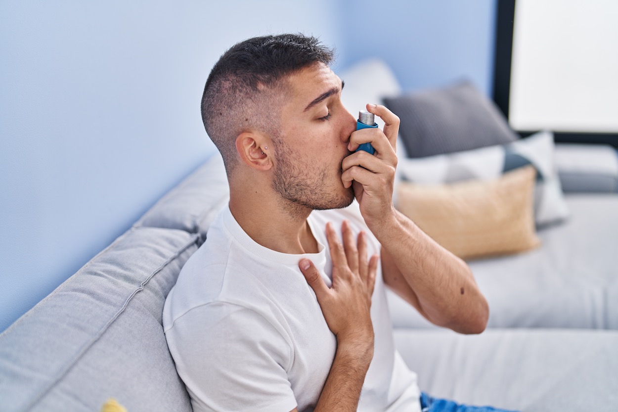 oral health and asthma, young Hispanic man using an inhaler for asthma
